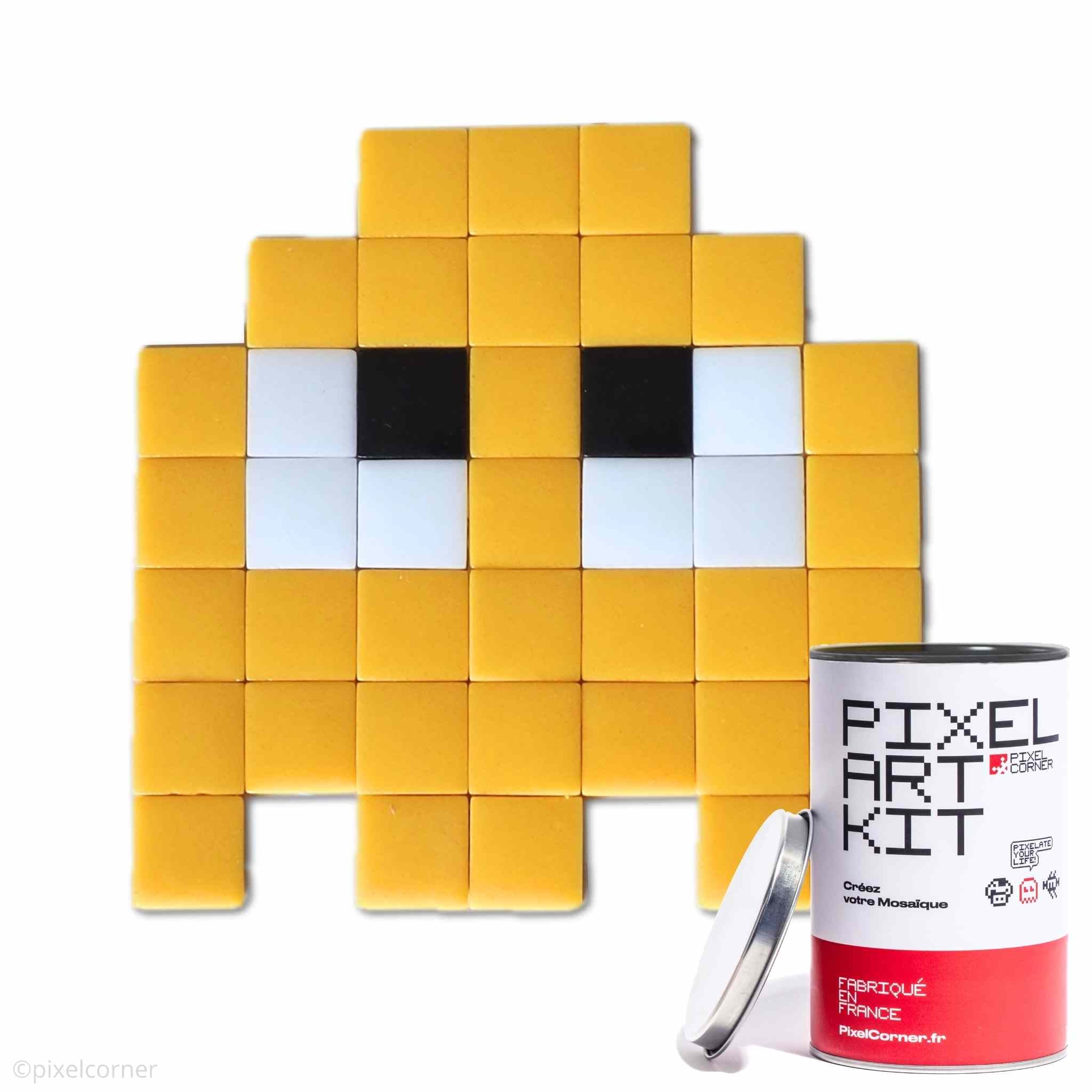 Un fantome jaune en pixel art retro gaming arcade pacman avec des carreaux de mosaïque de verre avec une boite de pixel art kit diy au premier plan