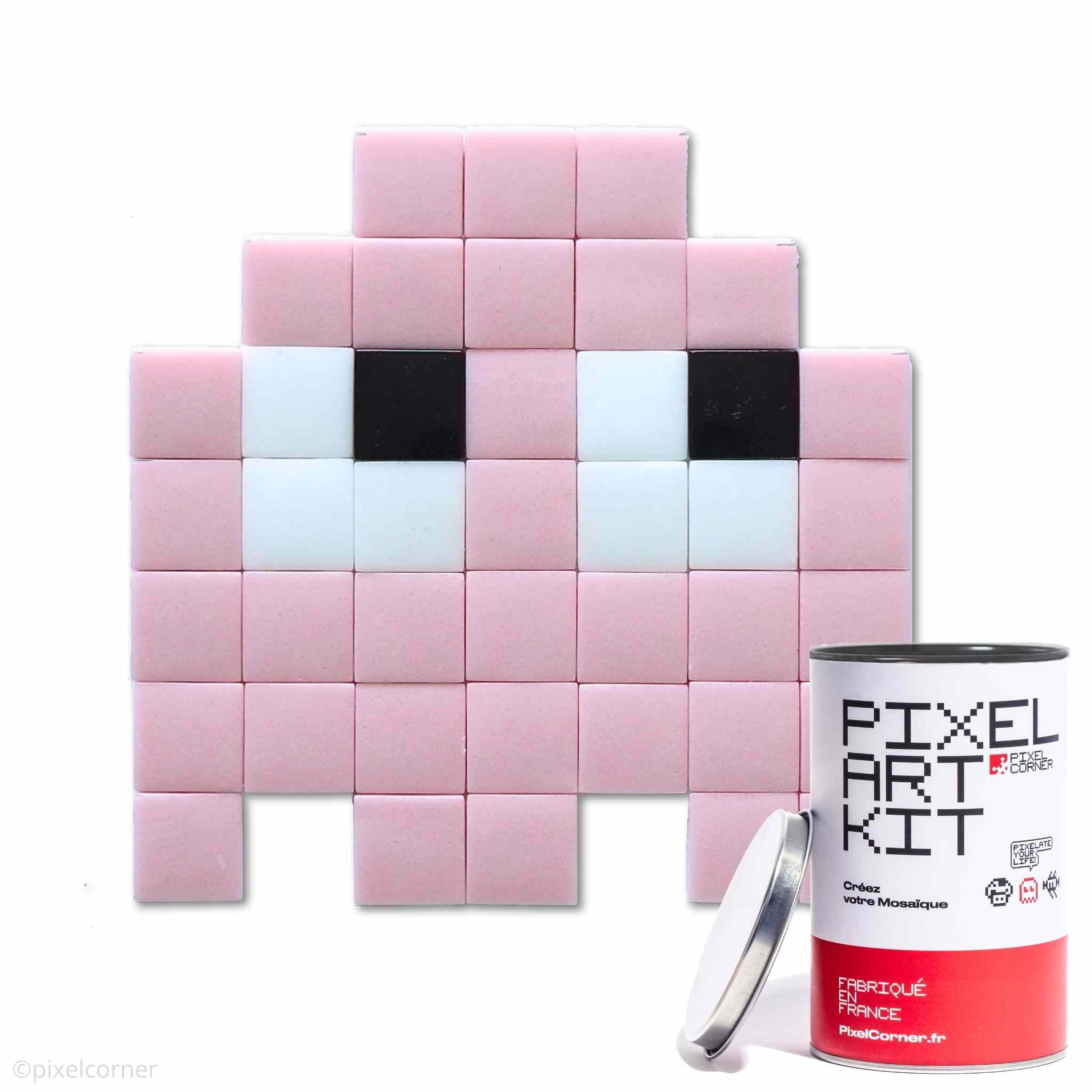 Un fantome rose en pixel art retro gaming arcade pacman avec des carreaux de mosaïque de verre avec une boite de pixel art kit diy au premier plan