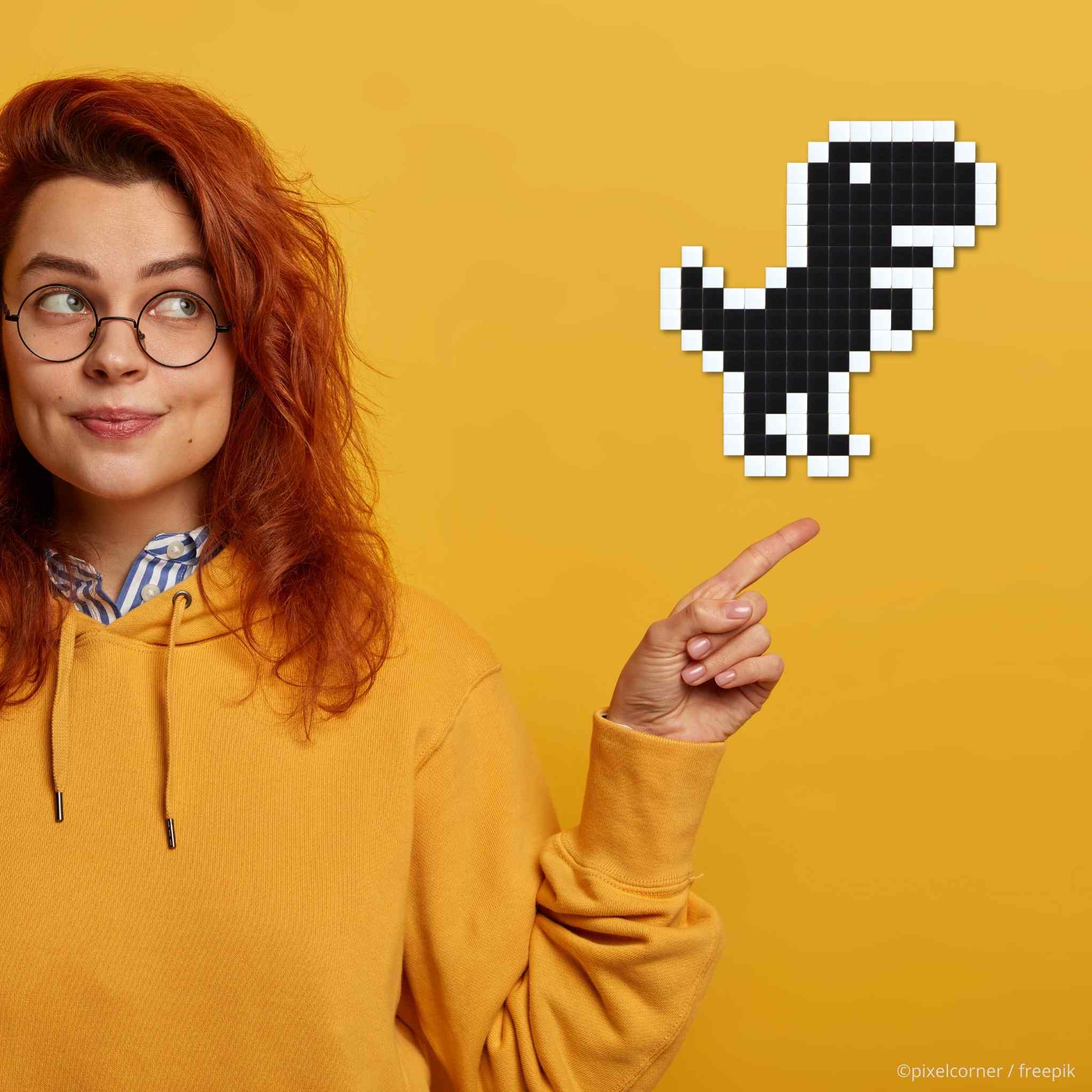 Une fille rousse en jaune sur fond jaune montre un dinosaure en pixel art diy réalisé en mosaïque de verre
