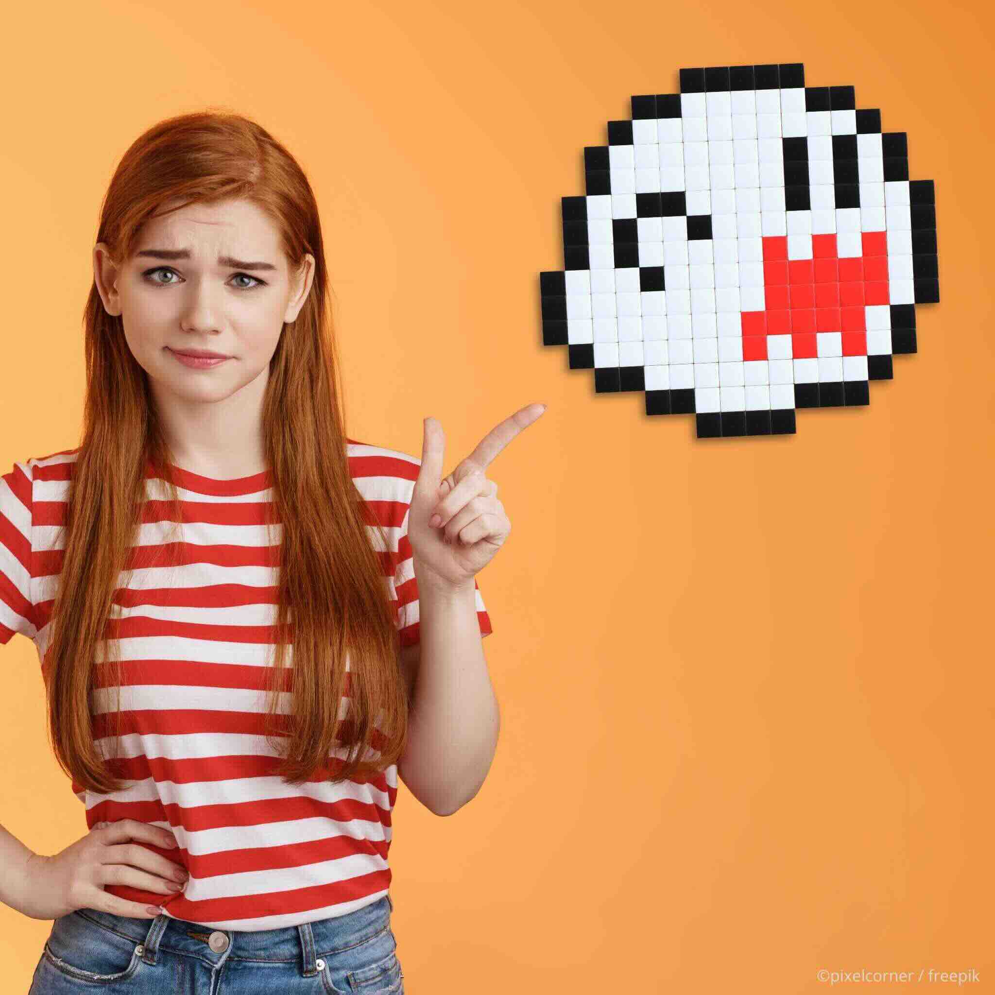 Une jeune fille à t-shirt rayé rouge sur un fond orange qui montre un superbe kit de mosaïque diy en pixel art du fantôme boo dans le jeu super mario