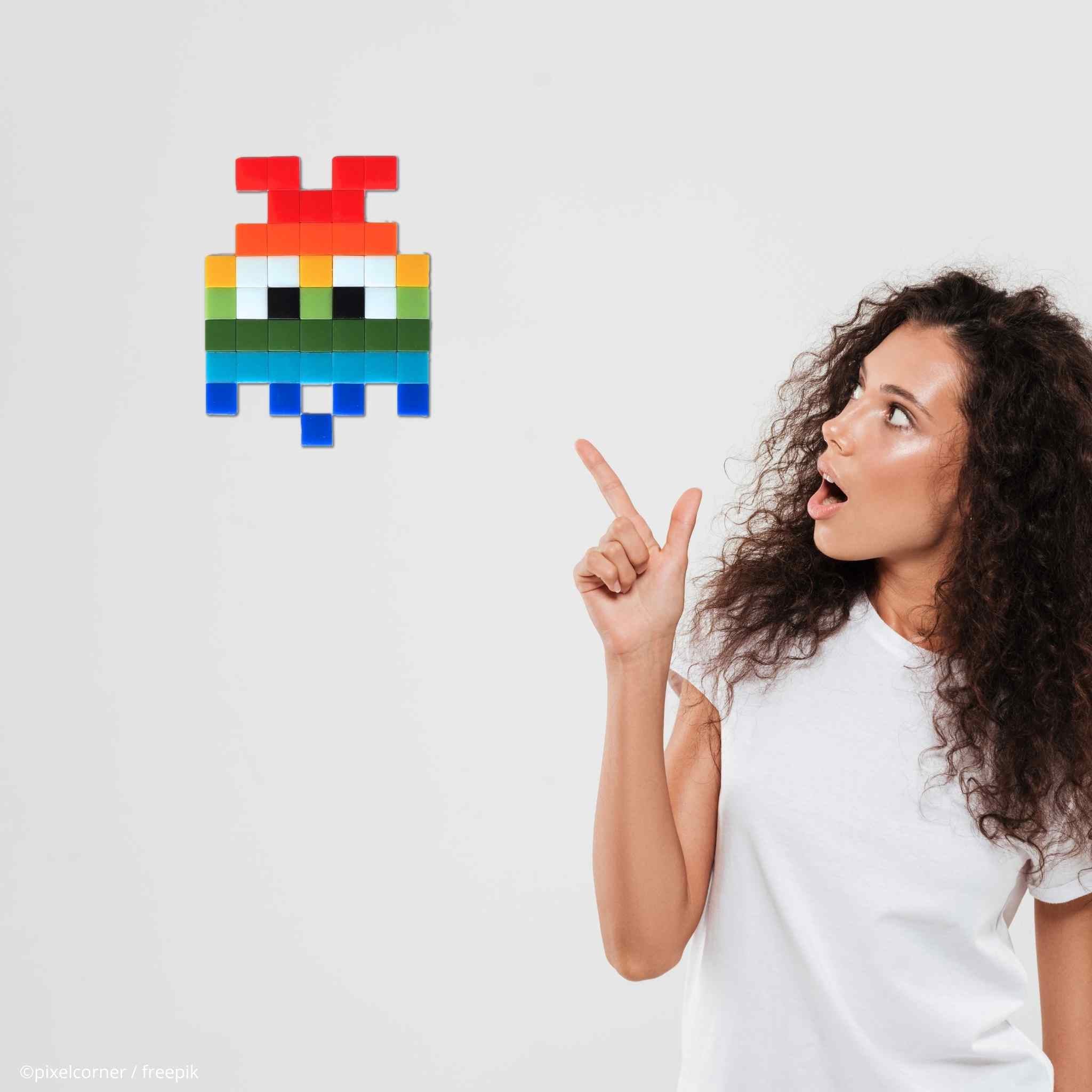 une femme frisée montrant un fantomes multicolore LGBT en pixel art sur un mur comme une décoration en mosaïque